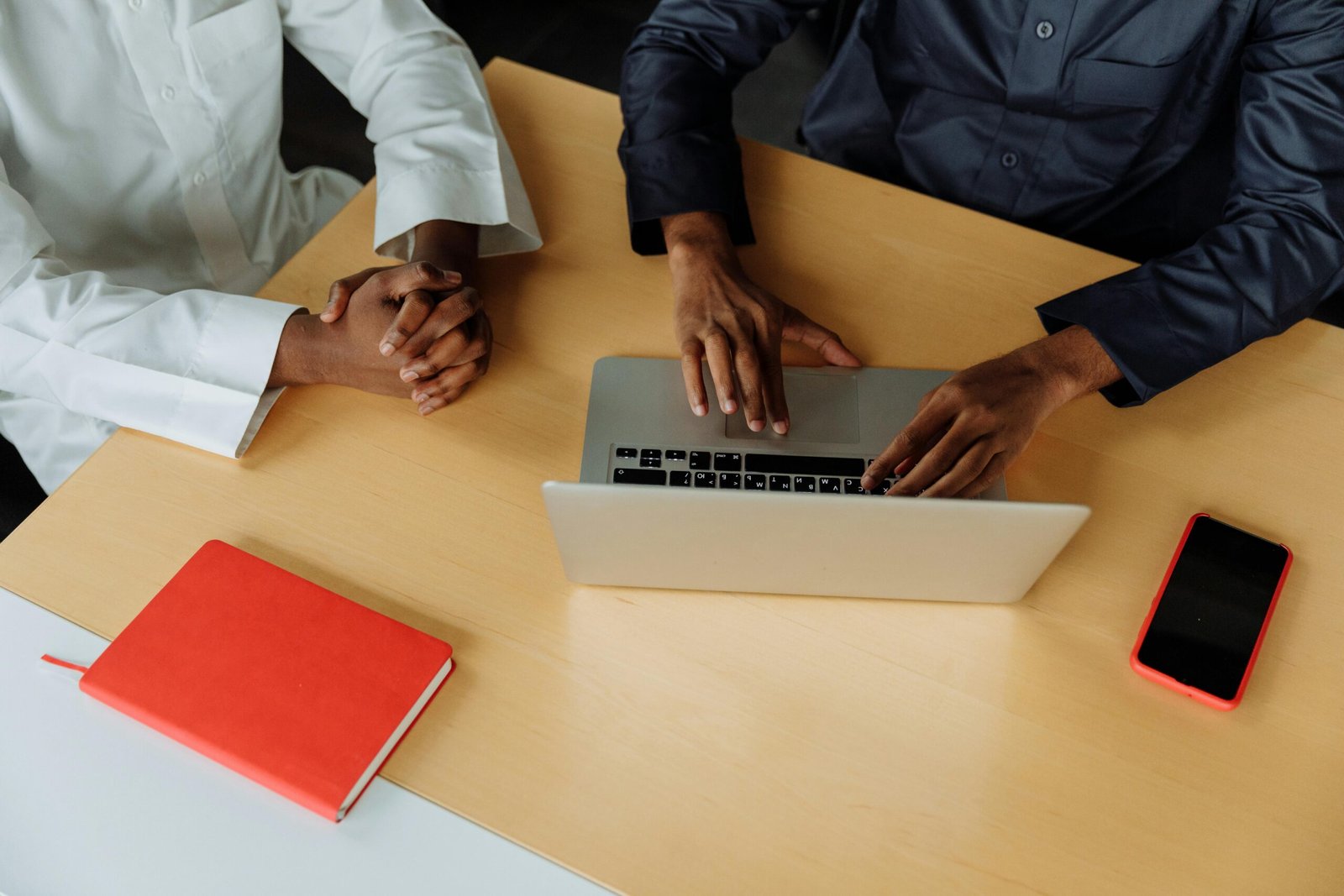 Home Two professionals collaborate using a laptop at a modern office desk. Meetings and productivity in one image.